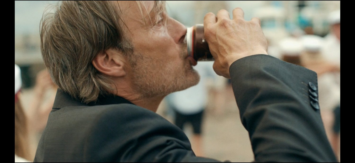 Un homme (incarné par Mads Mikkelsen) boit une canette de bière. Image issue du film "Drunk" réalisé par Thomas Vinterberg.
