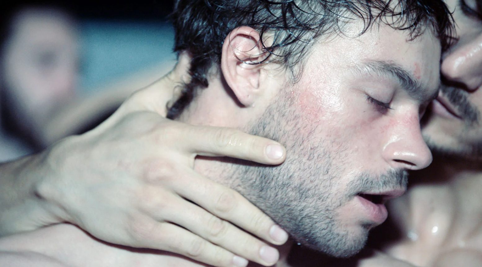 Gros plan sur un homme (Felix Maritaud) danse couvert de sueur et enlacé avec un garçon. Image issue du film "Sauvage" réalisé par Camille Vidal-Naquet.