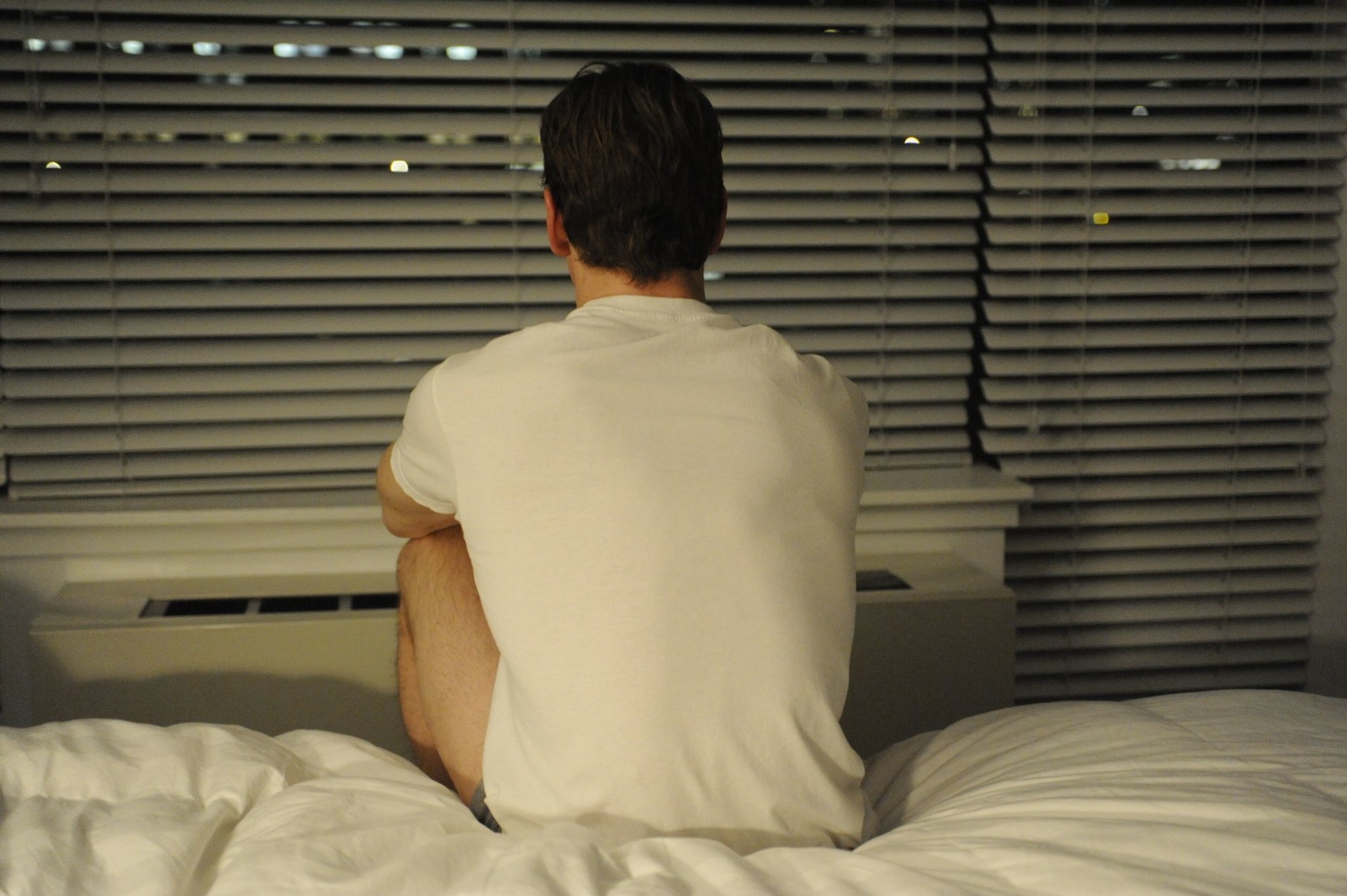 Le personnage incarné par Michael Fassbender est assis sur un lit, de dos. Image issue du film "Shame" réalisé par Steve McQueen.