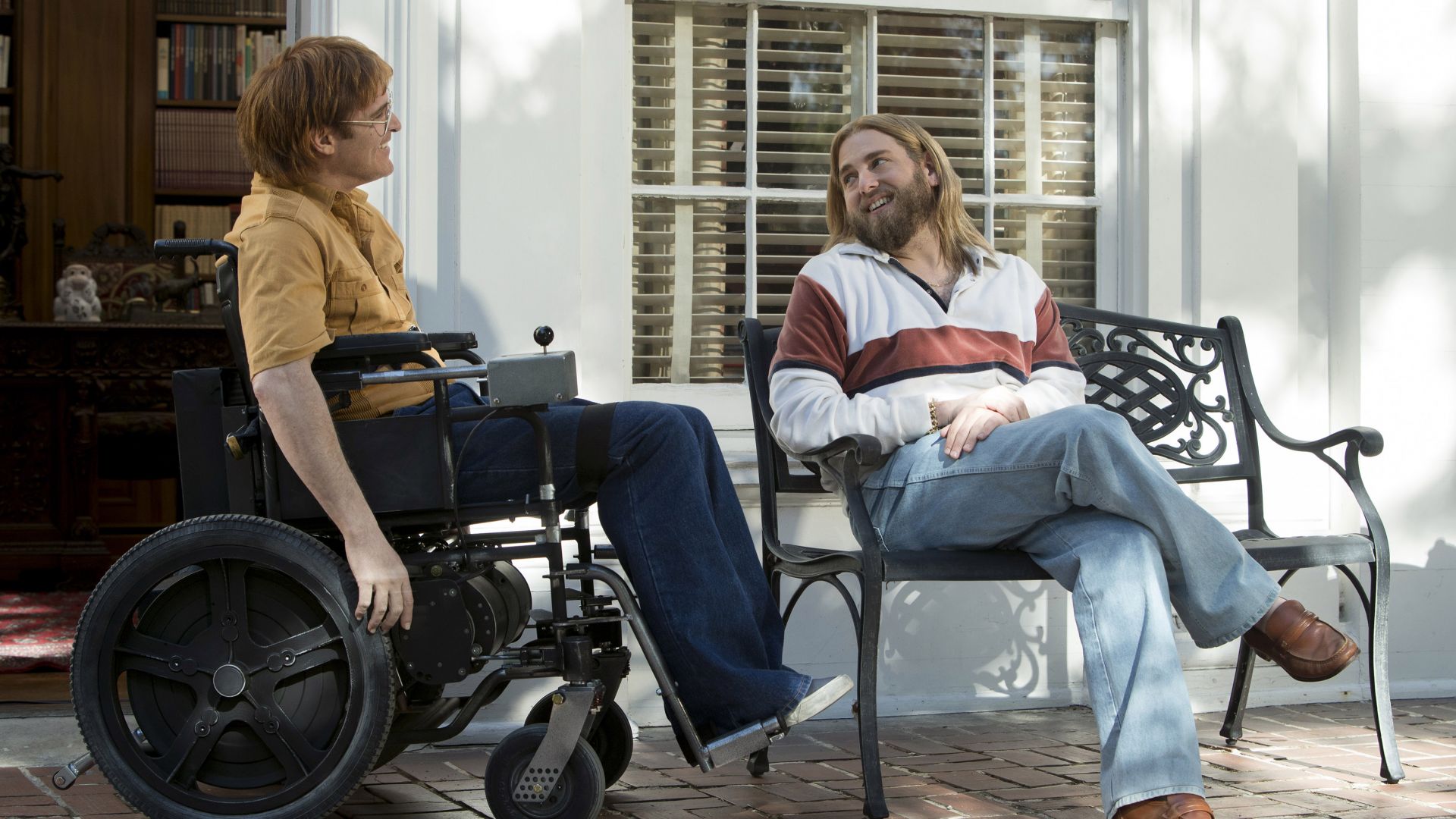 Deux hommes (incarnés par Joaqui Phoenix et Jonah Hill) avec des look rétro discutent. Image issue du film "Don't worry he won't get far on foot" réalisé par Gus Van Sant.